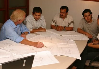Historical photograph of a meeting around a table with plans